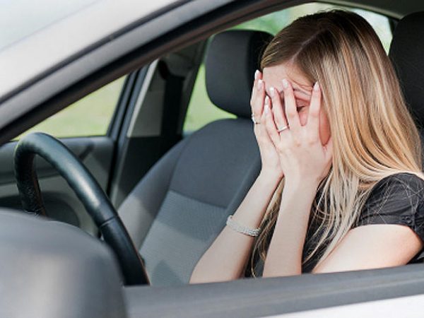 Distraught woman in car  who needs car odor removal service image.